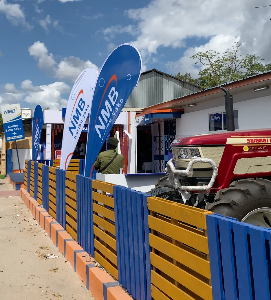 Row of NMB branded flags along the fairground fence next to an agri-financing tractor display
