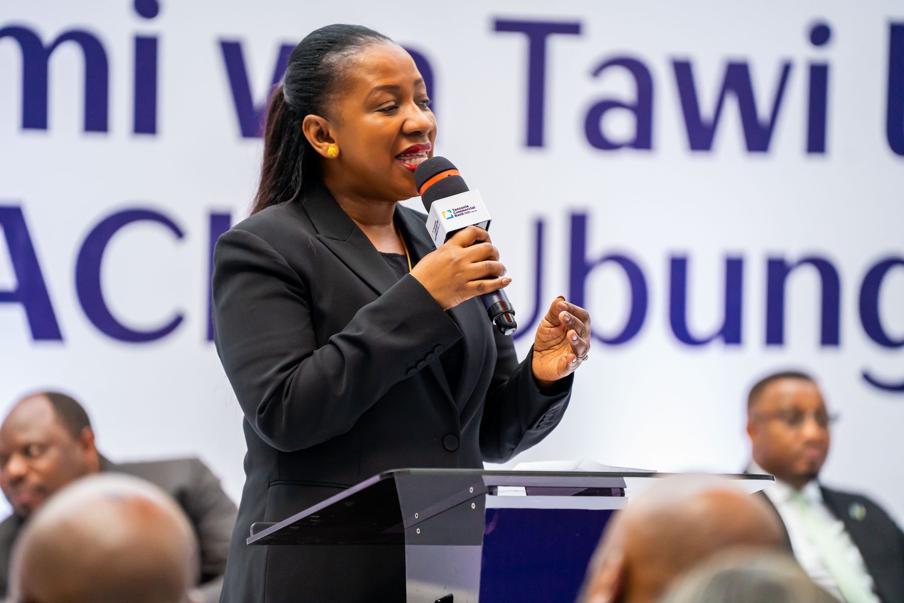 TCB executive speaking at the podium during the panel discussion, Ubungo branch launch